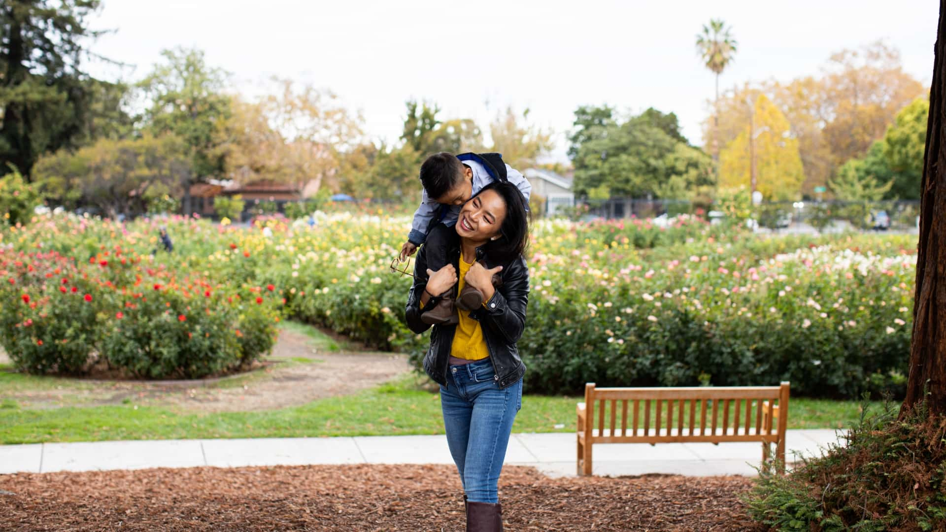 Woman walking through the park with her son on her back